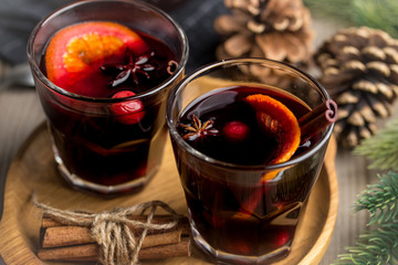 Christmas composition with spicy mulled wine and pine cones on wooden background