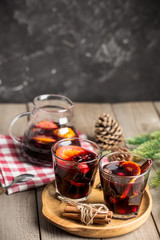 Christmas composition with spicy mulled wine and pine cones on wooden background