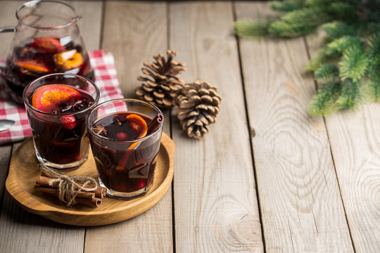 Christmas composition with spicy mulled wine and pine cones on wooden background