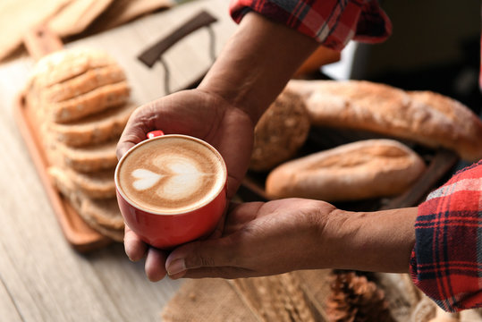 Heart latte coffee in barista hand.