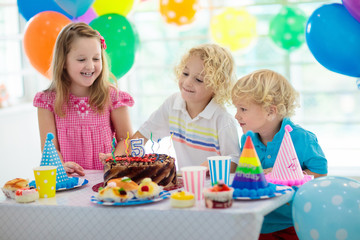 Kids birthday party. Child blowing out cake candle