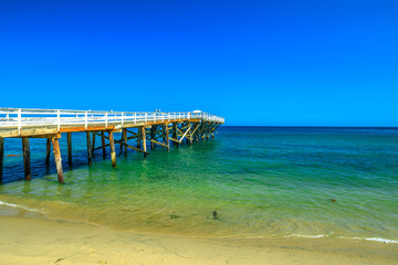 Paradise Cove Pier, a wooden pier in Paradise Cove beach, Malibu, California, United States. Wallpaper turquoise waters, copy space. Luxurious travel destination on Pacific Coast. Summer blue sky.