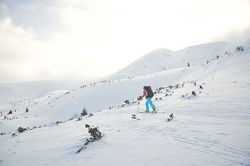 Fototapeta na wymiar Ski touring hiking alone up a summit in the winter mountains