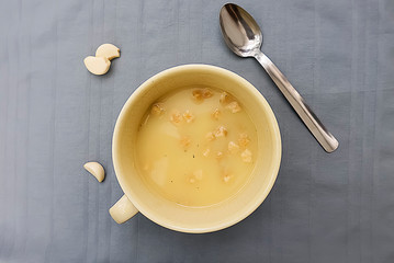 Champignon cream soup with croutons in a yellow cup on a gray background.