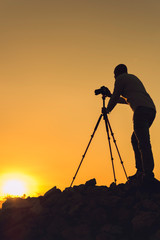 Silhouette of black photographer at sunset