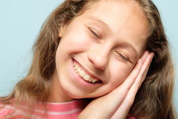 smiling girl pretending to be sleeping using hands as pillow. emotional facial expression.