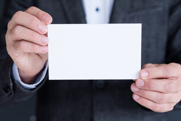 blank white paper in man hand. business announcement or advertisement.