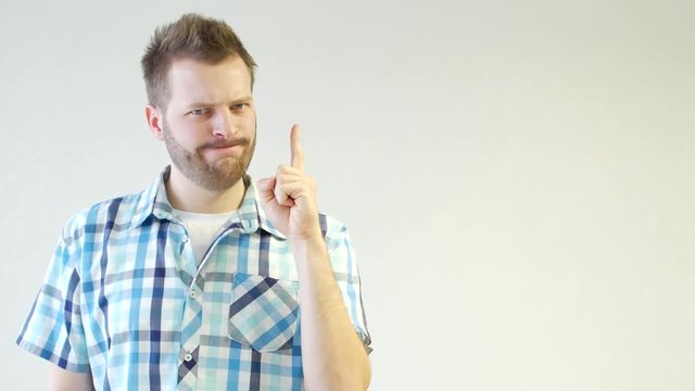 Young unshaven caucasian man in shirt is standing and waving his finger, idea, design, white background, close-up, copy space