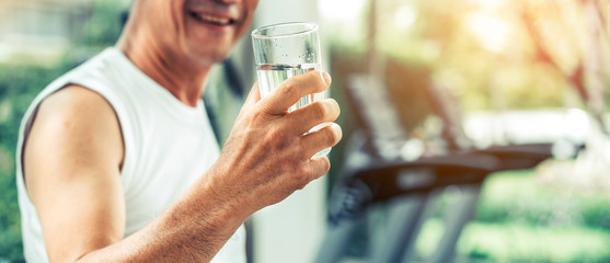 Senior man drink mineral water in gym fitness center after exercise. Elderly healthy lifestyle.