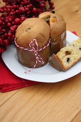 Italian Christmas cake called Panettone with a slice on a plate on wooden table. Traditional food to celebrate Christmas holidays