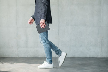 business man walking holding notebook in hand. smart casual fashion style