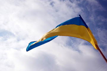 Ukrainian flag flying against the sky with clouds. Copy space. Yellow and blue colors. National symbol of Ukraine.