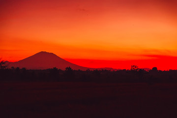 Bright colorful sunrise with silhouette of volcano in Bali