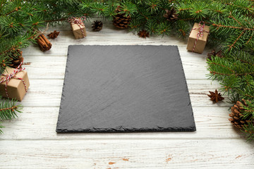 Perspective view. Empty black slate square plate on wooden christmas background. holiday dinner...