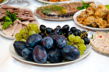 Plum fruits, grapes, meat, fish and roll on a festive New Year's table