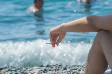 Male hand with a cigarette at the beach