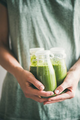 Winter seasonal smoothie drink detox. Female in dress holding bottles of green smoothie or juice in...