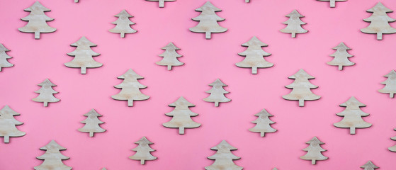 Creative and minimal  Christmas pattern made of wooden christmas trees. Pink background. Flat lay top view.