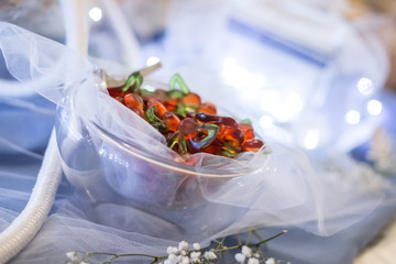 Red and green gummy candy on glass jar, decoration for ceremony on blue table with rope and lighted jar