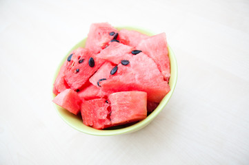 Fresh watermelon in green bowl on wooden table