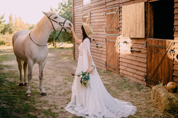 young boho style bride is stroking white horse
