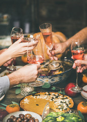 Traditional Christmas, New Year holiday celebration. Friends or family clinking glasses at festive table with turkey or chicken, vegetables, mushroom sauce