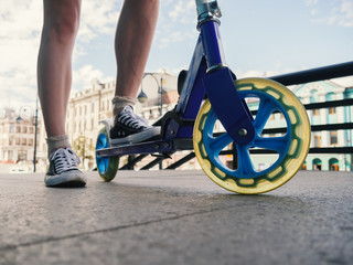 Naklejka premium Legs of young woman on kick scooter at street.
