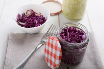 Homemade fermented cabbage in jars on a wooden table