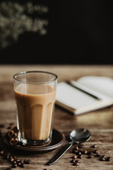 The vintage and stylish composition in kitchen interior with a glass of coffee with milk and cakes. Winter and autumn concept of morning breakfast. Black background.