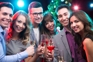 Young friends touching the glasses with each other