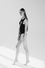 Naklejka premium Black and white shot of Fashionable young woman posing in black bodysuit, on grey