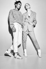 Black and white shot of Casual couple in red leaning against a grey wall