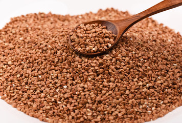 Wooden spoon full of buckwheat on a pile of buckwheat
