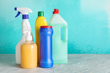 Bottles with detergents on table against color background