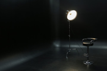 Fototapeta na wymiar Professional lighting equipment with chair on dark background