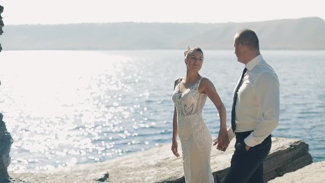 Young and beautiful wedding couple together on the slope of the mountain near sea. Lovely groom and bride. Slow motion