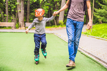 Dad teaches son to rollerblade in the park