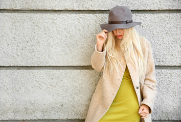 Beautiful fashionable woman near light wall