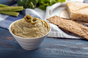 Bowl with tasty hummus on color wooden table