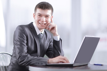 close up.smiling businessman sitting in front of open laptop