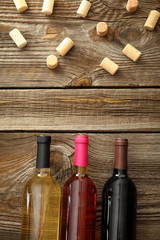 Bottles of different wine and corks on wooden background