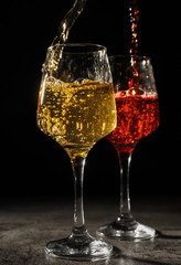 Pouring of wine into glasses on dark background