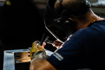Schweisser an der Arbeit mit Maske und Lederhandschuhe und Arbeitsbekleidung