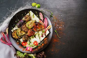 Vegan dish with roasted vegetables on black background