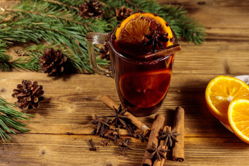 Christmas mulled wine with spices and fir tree branches and cones on wooden table