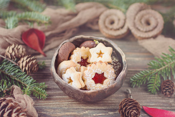 Christmas cookies in ceramic bowl, christmas tree branch and pine cones on a wooden background. Toned photo