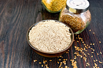 Flour linen in bowl with seeds in glass jars on dark board