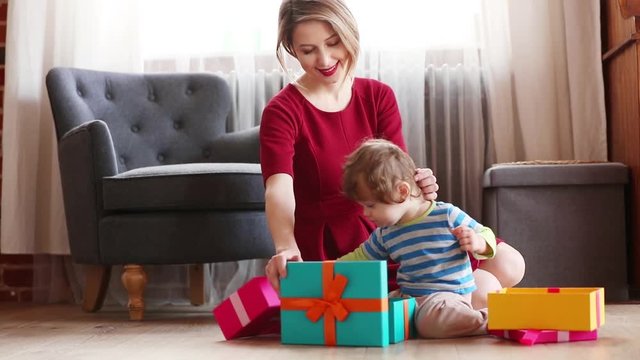 beautiful mother with son wrapping a gift boxes against the background of the scenery for Christmas in the kitchen - Powered by Adobe