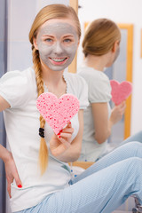 Woman having grey face mask holding heart sponge