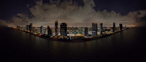 Aerial night drone panoramac photo coastal city highrise tower illuminated